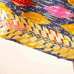 Close-up of a colorful fabric with gold leaf patterns on a white background