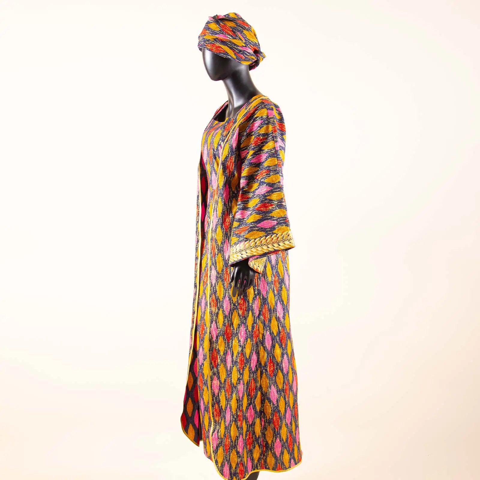 Mannequin wearing a colorful patterned dress and headscarf on a white background