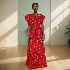 Model wearing a red dress with yellow patterns in a bright room.